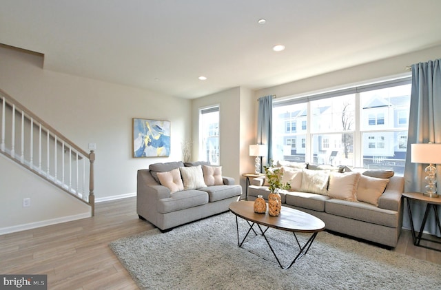 living room with recessed lighting, stairway, baseboards, and light wood-style flooring