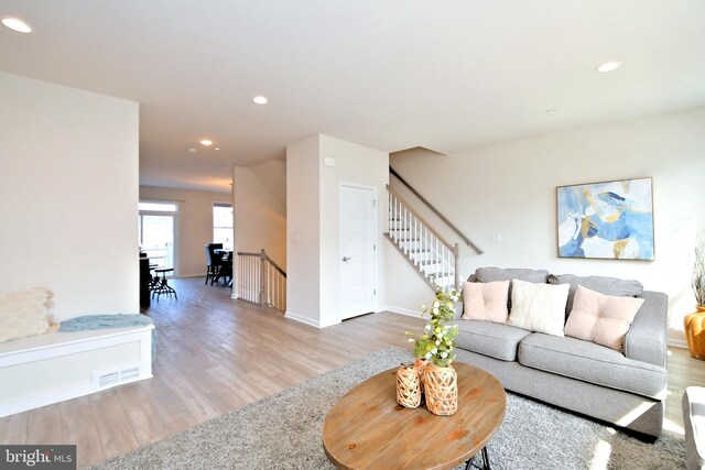 living room with visible vents, recessed lighting, stairway, and light wood-type flooring