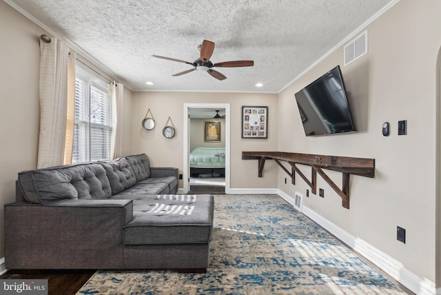 living room featuring baseboards, visible vents, a textured ceiling, and ornamental molding