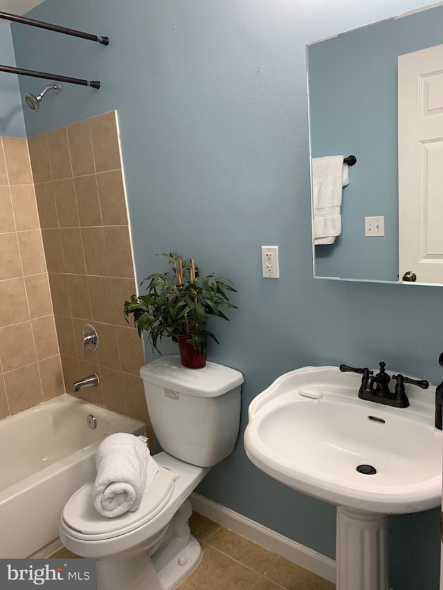 bathroom featuring shower / bathtub combination, toilet, a sink, tile patterned flooring, and baseboards