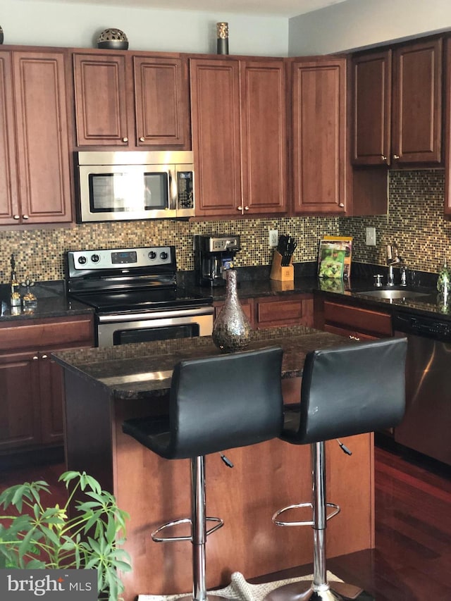 kitchen with a breakfast bar, a center island, tasteful backsplash, appliances with stainless steel finishes, and a sink