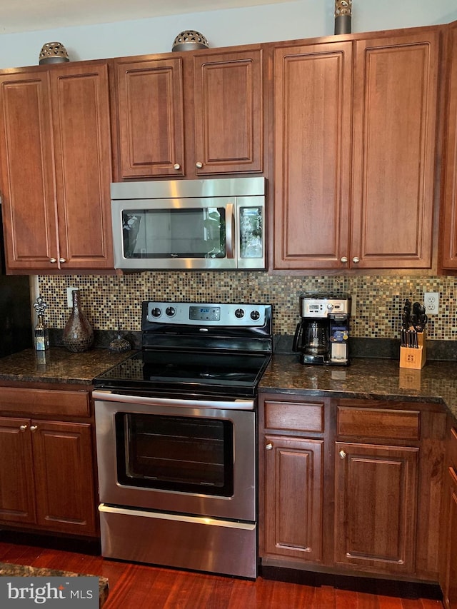 kitchen featuring dark wood-type flooring, stainless steel appliances, decorative backsplash, and brown cabinetry