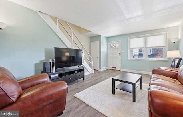 living room featuring stairs, baseboards, and wood finished floors