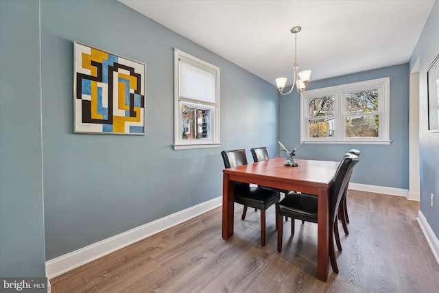 dining area featuring a chandelier, wood finished floors, and baseboards