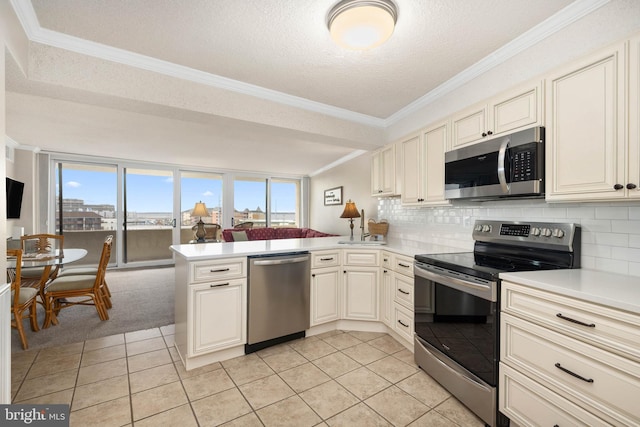 kitchen with ornamental molding, a peninsula, stainless steel appliances, light countertops, and backsplash