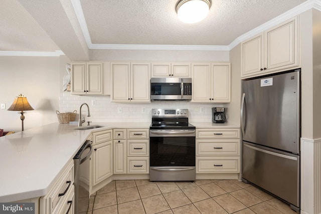 kitchen with cream cabinetry, light countertops, appliances with stainless steel finishes, a sink, and a peninsula