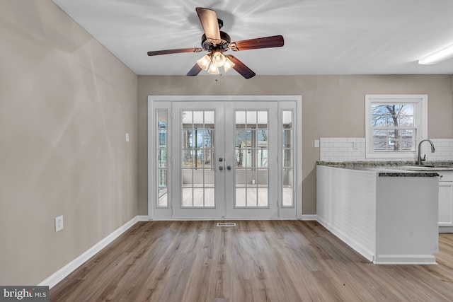 doorway featuring light wood-type flooring, french doors, a sink, and baseboards