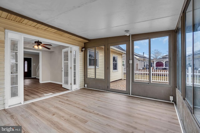 unfurnished sunroom featuring a ceiling fan and french doors