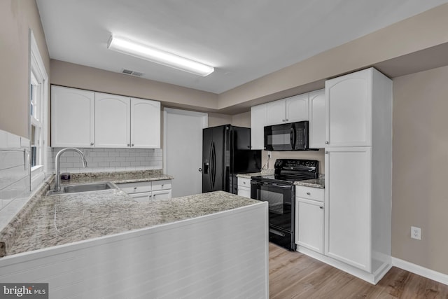 kitchen featuring a sink, visible vents, white cabinets, light wood-type flooring, and black appliances