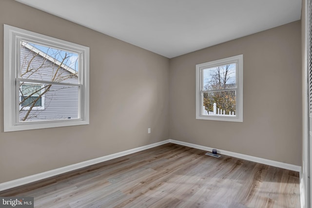 empty room featuring visible vents, baseboards, and wood finished floors