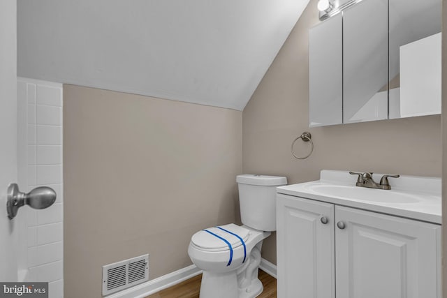 bathroom with visible vents, toilet, lofted ceiling, wood finished floors, and vanity