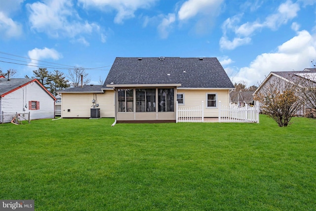 rear view of property featuring a shingled roof, a lawn, cooling unit, and a sunroom