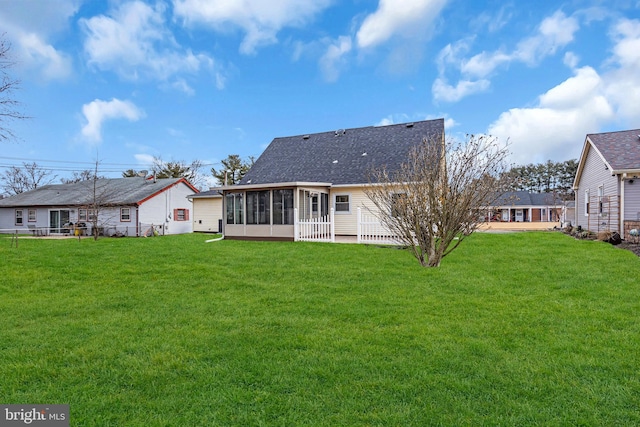 rear view of property with a yard, a shingled roof, and a sunroom