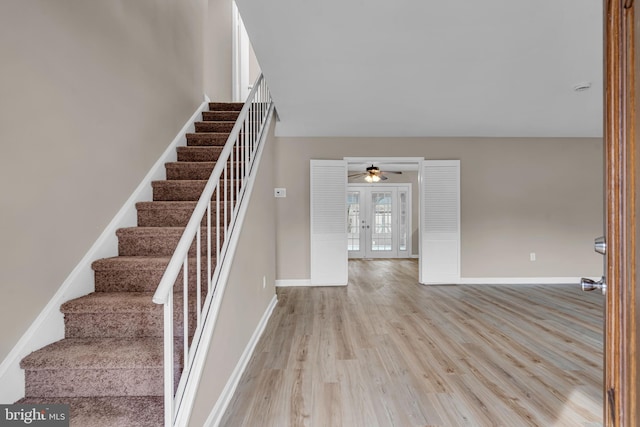 stairs with french doors, wood finished floors, and baseboards