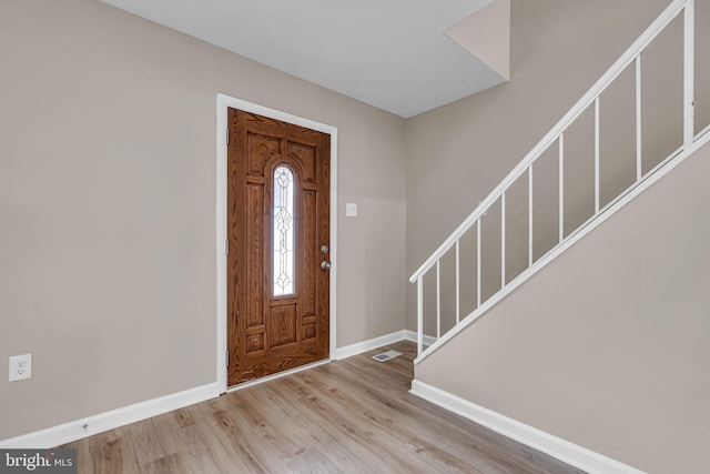 foyer with stairs, wood finished floors, visible vents, and baseboards