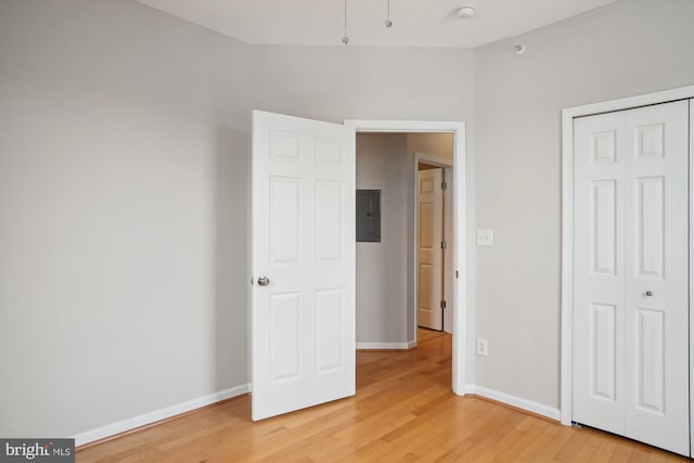 unfurnished bedroom with light wood finished floors, electric panel, and baseboards