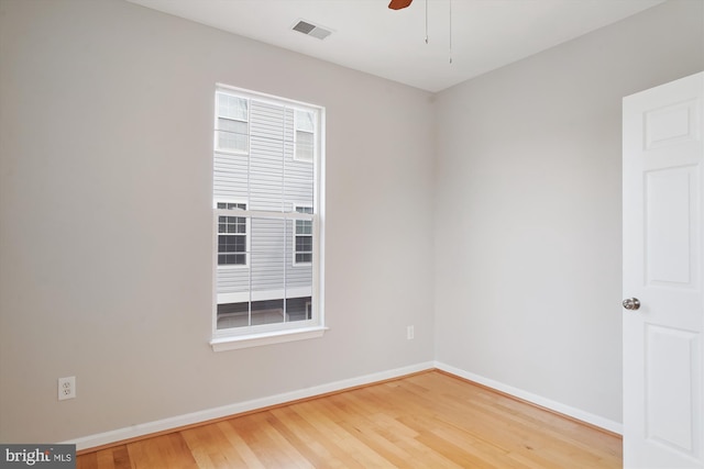 spare room with a ceiling fan, baseboards, visible vents, and wood finished floors