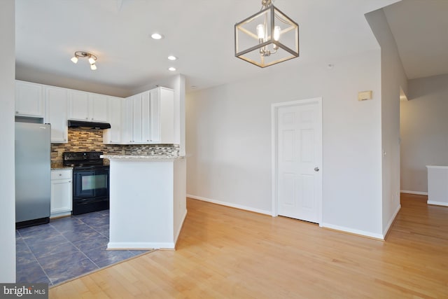 kitchen featuring white cabinets, decorative backsplash, freestanding refrigerator, under cabinet range hood, and black range with electric cooktop