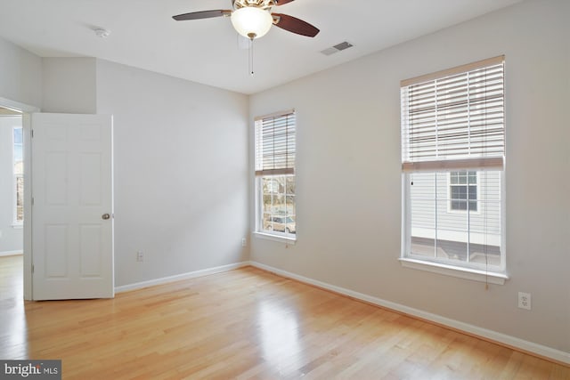 unfurnished room featuring wood finished floors, visible vents, and baseboards