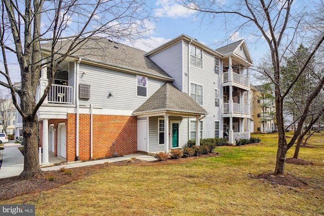 exterior space with brick siding, a front yard, and a shingled roof