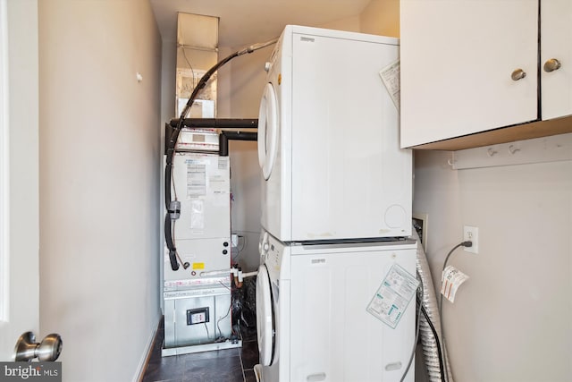 laundry room featuring stacked washer and dryer and cabinet space