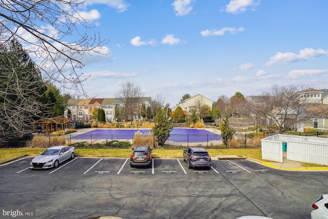 uncovered parking lot featuring a residential view and fence