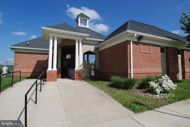 view of front of house with brick siding, a shingled roof, and fence