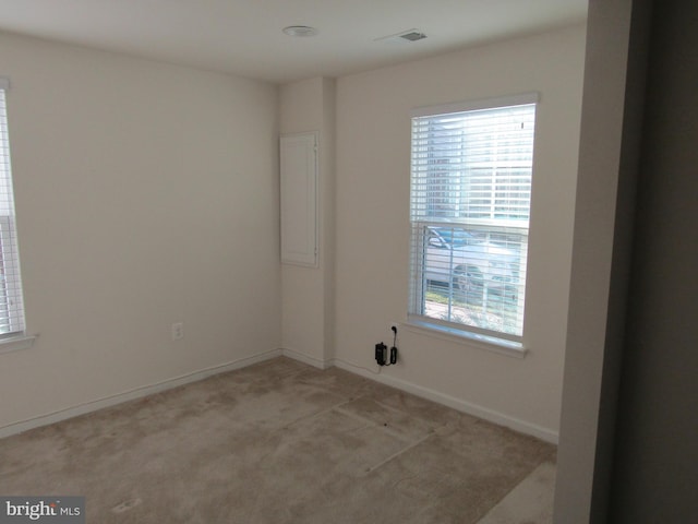 empty room featuring light carpet, visible vents, and baseboards