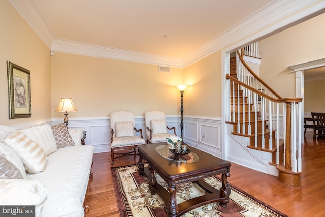 living area featuring visible vents, crown molding, stairs, wainscoting, and wood finished floors