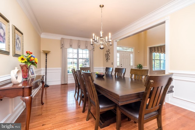 dining room featuring a chandelier, wainscoting, light wood-type flooring, and ornamental molding