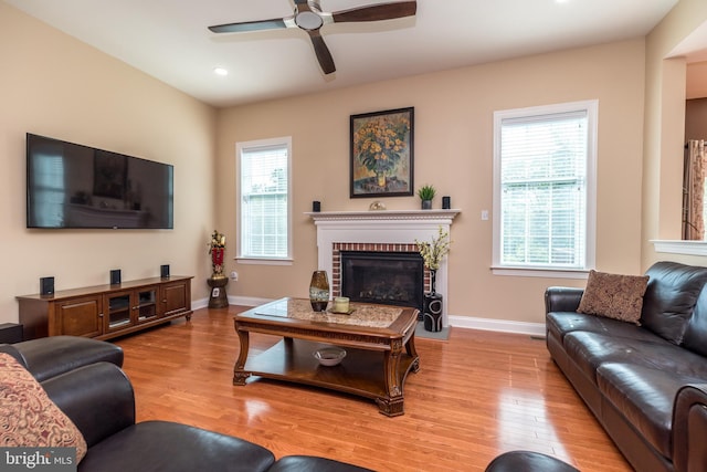 living area featuring a brick fireplace, baseboards, and wood finished floors