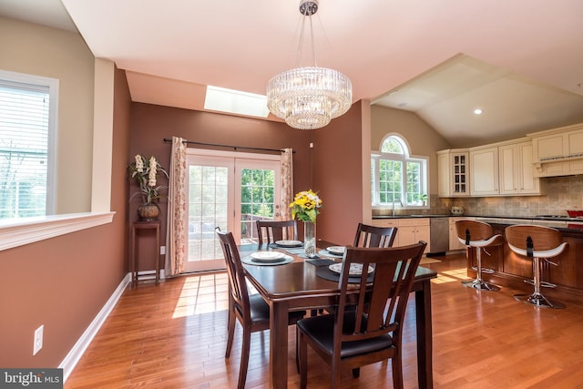 dining area featuring baseboards, lofted ceiling, an inviting chandelier, and light wood-style flooring