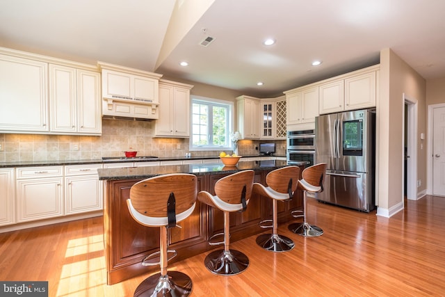 kitchen with visible vents, tasteful backsplash, a center island, stainless steel appliances, and light wood finished floors