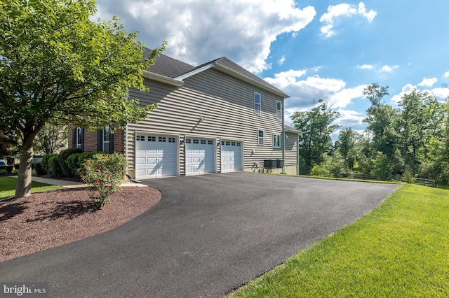 view of home's exterior with aphalt driveway, central air condition unit, a lawn, and a garage