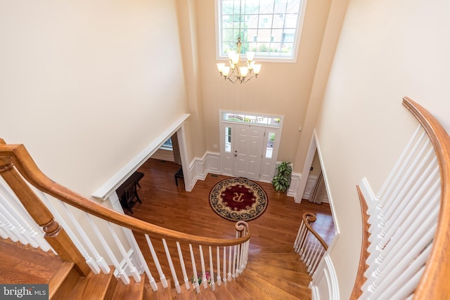 foyer entrance with a chandelier, wood finished floors, a towering ceiling, and stairway