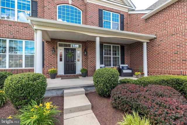 doorway to property with brick siding and covered porch