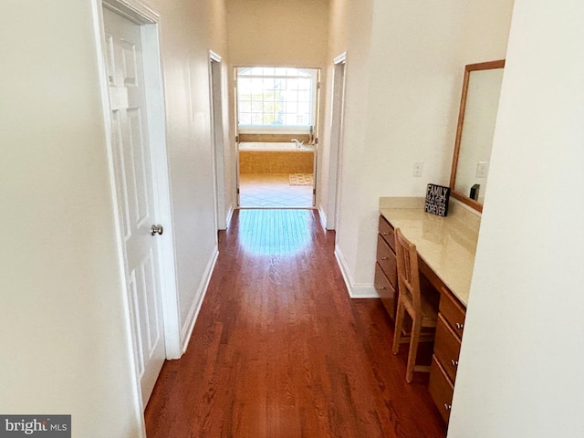 hallway featuring dark wood-type flooring and baseboards