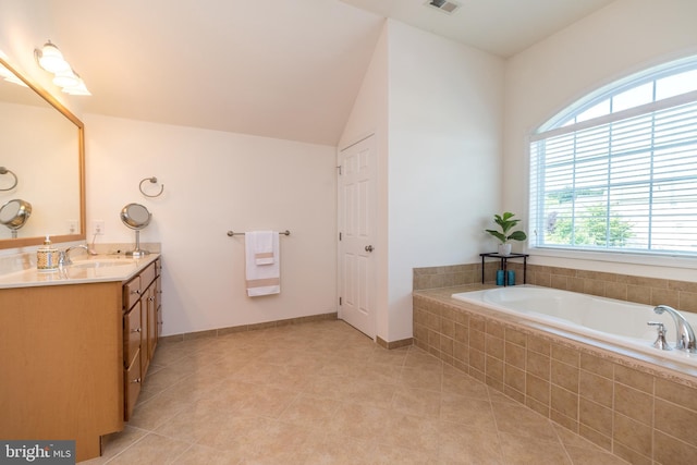 bathroom with tile patterned flooring, baseboards, lofted ceiling, a garden tub, and vanity