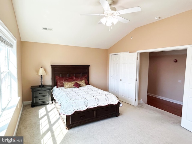 bedroom featuring a closet, visible vents, light colored carpet, and vaulted ceiling