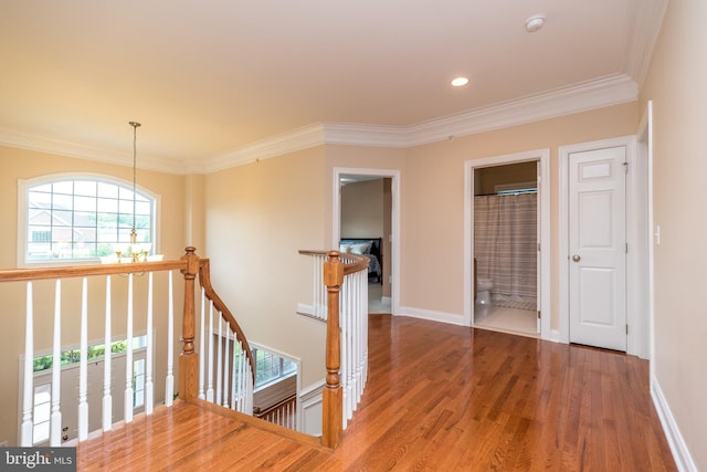 corridor with baseboards, an upstairs landing, wood finished floors, and a chandelier