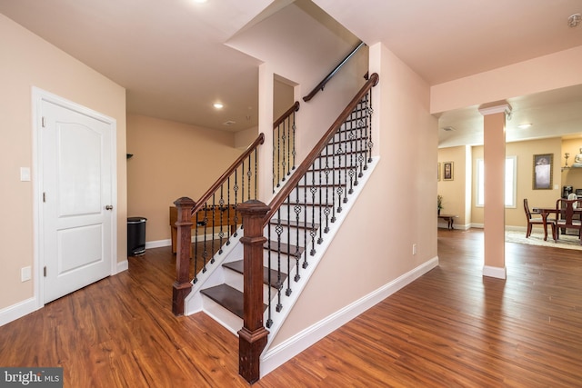 stairway featuring recessed lighting, decorative columns, baseboards, and wood finished floors