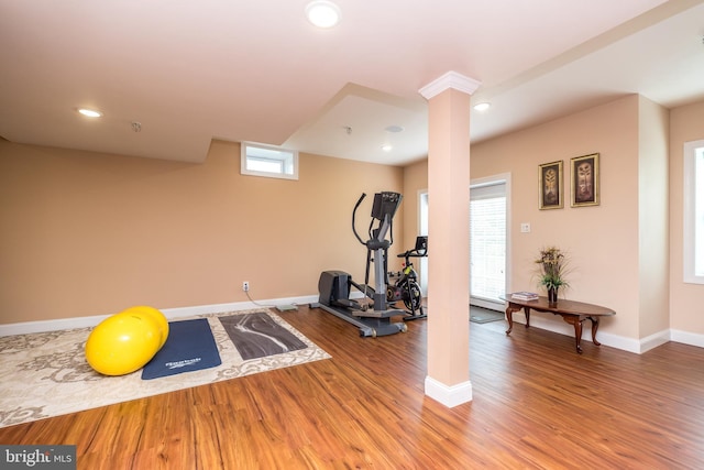 exercise room with recessed lighting, decorative columns, baseboards, and wood finished floors