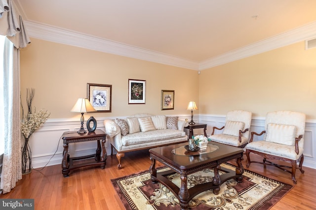 living room with a wainscoted wall, wood finished floors, and ornamental molding