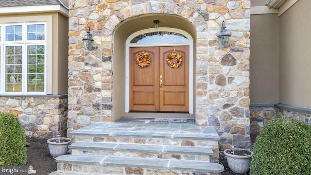 view of exterior entry featuring stone siding and stucco siding