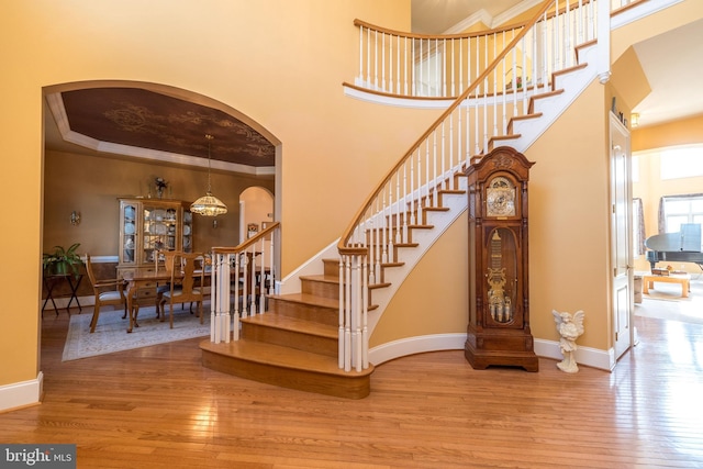 stairway with a high ceiling, baseboards, and hardwood / wood-style floors