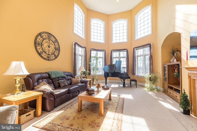 carpeted living room featuring baseboards and a towering ceiling