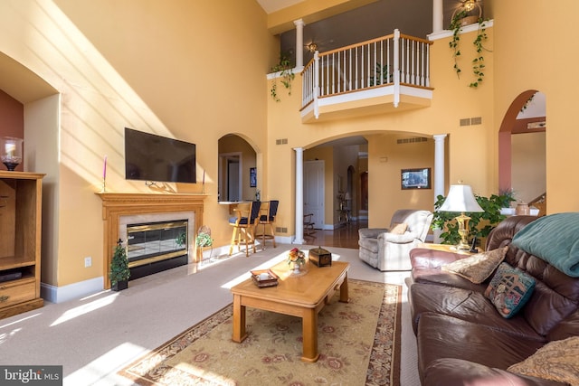 living area with visible vents, arched walkways, carpet, and a high end fireplace