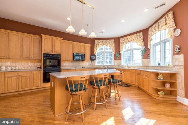 kitchen featuring visible vents, black appliances, light countertops, and light wood-type flooring