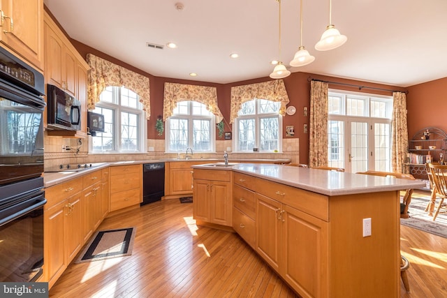 kitchen with black appliances, light wood-style flooring, light countertops, and light brown cabinetry