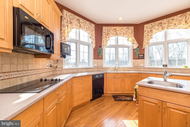 kitchen with black appliances, light countertops, light wood-style floors, and a sink